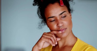 Düşünceli, genç bir kadın. Yüze yakın çekim. Düşünerek karar verme. 20 'li yaşlarda, Afrika kökenli derin düşünen kadın portresi.