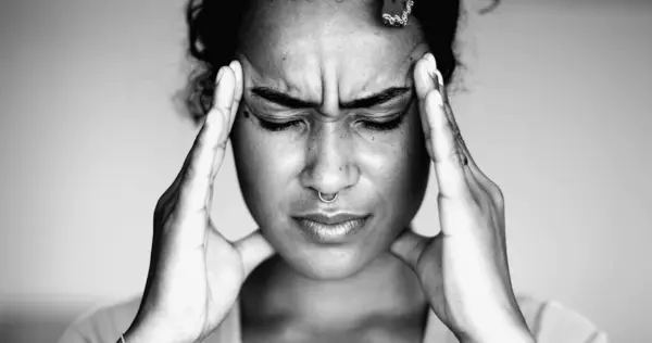 Overwhelmed young African American woman pressing head side temples feeling mental pressure and anxiety, close-up face of person feel stress and indignation