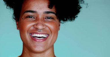 Genç siyahi bir kadın gülümsüyor ve gülüyor. Gerçek otantik yüz ifadesi. 20 'li yaşlarda Afrika kökenli biri kameraya bakıyor.