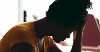 Genç Afrikalı Amerikalı kadın evde depresyonla boğuşuyor. Stres ve keder altında eziliyor. Baş ağrısı çeken elleri şakaklara koyuyor.