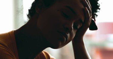 Depresyonda olan genç bir kadın akıl hastalığından muzdarip. Stres ve sessiz umutsuzluktan bunalmış bir siyahi, elleriyle başını tutuyor.