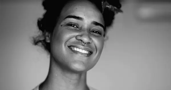 stock image Monochromatic Portrait of a Happy Young Black Brazilian Woman Smiling with Friendly Demeanor, Joyful Close-up on White Background, black and white