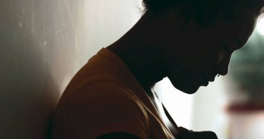 Zor zamanlarda mücadele eden genç Afrikalı Amerikalı kadın elleri göğsünde aşağıya bakıyor ve siluette yardım ve destek arıyor. Yardım isteyen siyahi bir Latin 'in profili