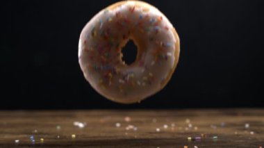 Büyük beyaz donut yavaşça masa yüzeyine düşüyor. Makro mercekli ve siyah arka planlı 800 fps, sürahi tatlı atıştırmalık.