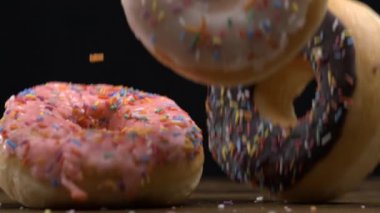 Büyük çörekler siyah arka planda çok yavaş çekimde masa yüzeyine düşüyor. Makroda üç karbonhidratlı yiyecek 800lerde yüksek hızlı bir kamerayla yakalandı.