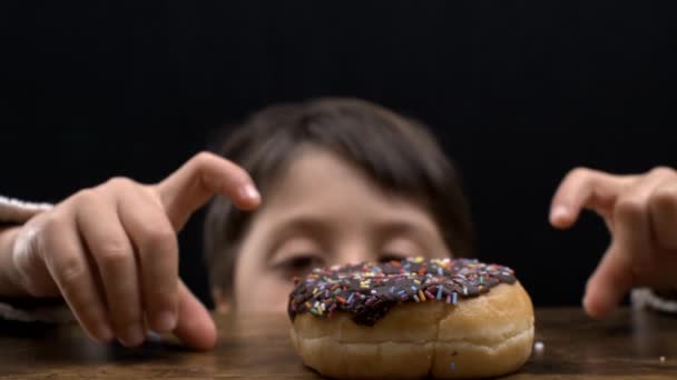 Καθυστερημένη Ικανοποίηση Νεαρό Αγόρι Ατενίζοντας Επίμονα Στο Donut Στο Τραπέζι — Αρχείο Βίντεο