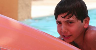 Yüzme havuzunda şişme şiltenin üstünde oynayan samimi çocuk.