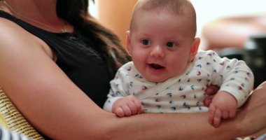 Baby in mother arms smiling and feeling happy