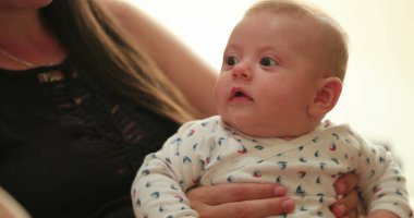 baby with mom listening to conversation learning about the world candid