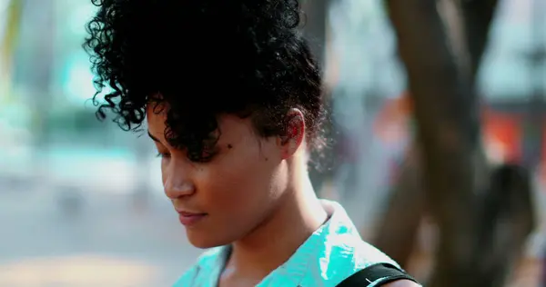Portrait of a Pensive young black woman standing outdoor in peaceful meditative state, close-up face in tracking shot during sunny day and contemplative emotion