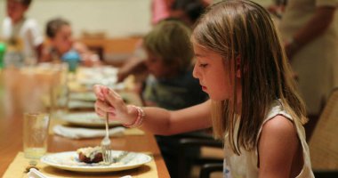 Küçük kız çocuklarla akşam yemeği yiyor.