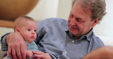 Büyük baba kucağında bebek torunu kanepesinde yatıyor.