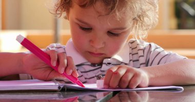 Little boy holding color pen drawing on paper