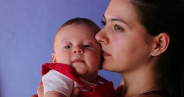 Mother holding baby hugging and kissing love and care