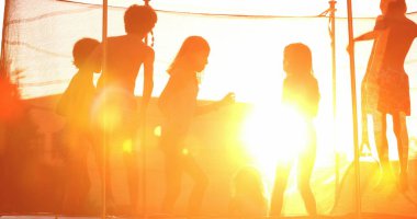 Çocuklar altın saat günbatımında trambolinde zıplıyorlar. Çocuklar alevlerle zıplıyorlar.