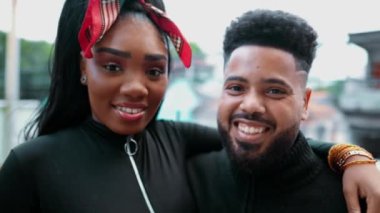Mutlu Güney Amerikalı genç adam ve kadın birlikte takılıyor ve kameraya gülümsüyor. Afrika kökenli iki siyah 20 'li yaşların portresi. Yakından çekilmiş yüzler ve sarılıyorlar.