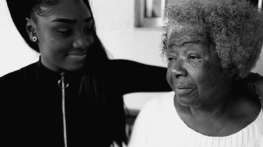 Sevecen torun, 80 'lerin Afro-Amerikan büyükannesine yoğun monokromatik, siyah beyaz, el ele tutuşmuş ve alnını öpmüş bir şekilde destek veriyor.