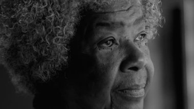 Yansıtıcı 80 'lerin Afrikalı Amerikalı kıdemli bayan pencereden dışarı bakıyor, Derin Düşünce ve Düşünce, Yaşlılığı simsiyah beyaz, tek renkli