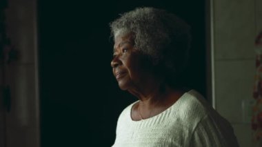 Meditasyon yapan son sınıf öğrencisi kadın mutfak penceresinin yanında durup içeriden dışarıya bakıyor. Güney Amerika 80 'lerin yaşlıları ciddi tefekküre sahipler.