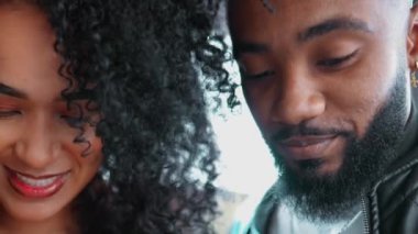 Genç Afro-Amerikan erkek ve kadın cep telefonu cihazları kullanıyor, yakın çekim yüzleri ve elleri akıllı telefona bakıyor, modern teknoloji ile meşgul çift