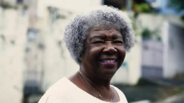 Şehir ortamında kameraya gülümseyen, gri saçlı, yakından çekimli, arkadaş canlısı bir siyahi kadın. 80 'lerdeki Afrikalı Amerikalı Yaşlı Kadın