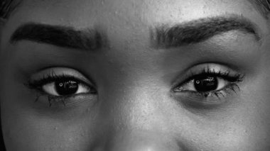 Afrika kökenli Amerikalı genç bir kadının yoğun bakışları makro yakından tek renkli, siyah beyaz kameraya bakıyor.