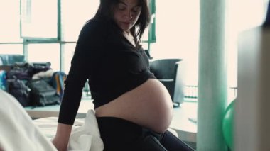 Doğum öncesi kasılmalar sırasında hastanede yatağının yanında oturan hamile bir kadın. Doğumdan önce üçüncü üç aylık hamilelik