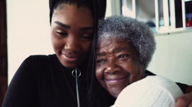 Afrikalı Amerikalı büyükannenin portresi ergen torununu şefkatle kucaklıyor, nesiller arası sevgi dolu bir ilişki içinde.