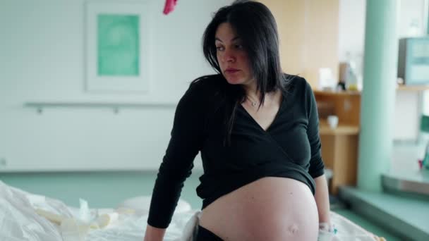 Pensive 30S 妊娠中の女性 病院のベッドでリーニング クリニックでの労働契約中 — ストック動画