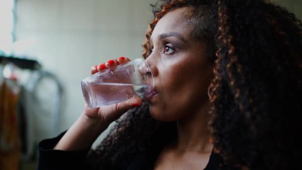 Одна Вдумчивая Черная Женщина Средних Лет Пьет Воду Глядя Вдаль — стоковое видео