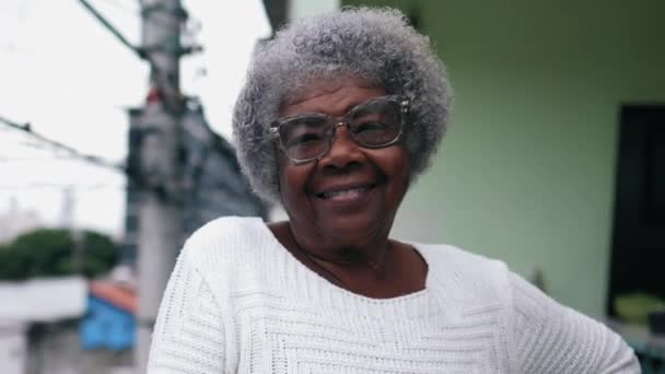 80年代快乐的非洲裔美国老年妇女站在阳台上 面对着背景为城市环境的相机微笑 一位来自南美洲的巴西黑人老太太 — 图库视频影像