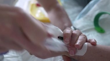 Hemşirenin eli hastanın eline serumla serumsal kateter takıyor. Hastane ekipmanları ve rutin