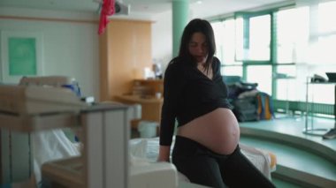 Doğum sancısı çeken, 30 'lu yaşlarda, doğum sancısı çeken bir kadın hastahane yatağında oturan hamile kadın.