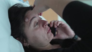 Kafası meşgul bir kadın, telefondaki profil yüz ifadesiyle konuşuyor. Cep telefonu cihazıyla konuşan kişinin gerçek endişeli duyguları, gerçek hayat ifadesi.