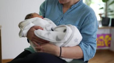 Anne kucağında yeni doğmuş bir bebek, bebeğin ilk günlerinde kollarını tutuyor.