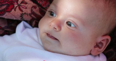 Happy newborn baby looking and observing laid in ground