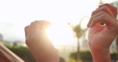Hands held together with sunlight flare shining in the background