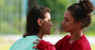 Two young women hugging each other outdoors. Empathic loving hug embrace