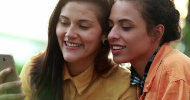 Two girls watching streaming content online. Women looking at  phone screen laughing