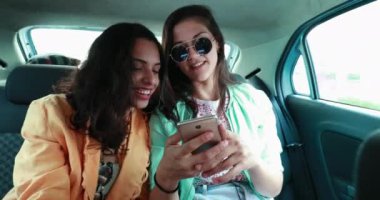 Authentic friends laughing together while sharing content on smartphone device