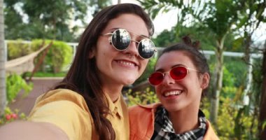 Funny girls holding camera and taking selfie of themselves while grimacing and posing