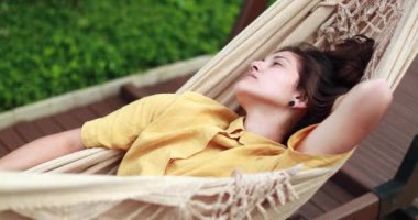 Young woman relaxing lying on hammock
