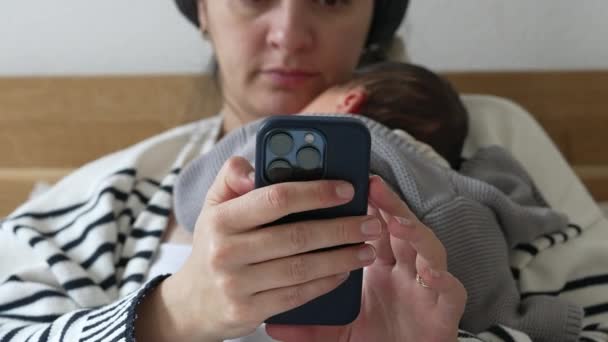 Close Mother Holding Cellphone Device While Holding Newborn Baby Resting — Stok video