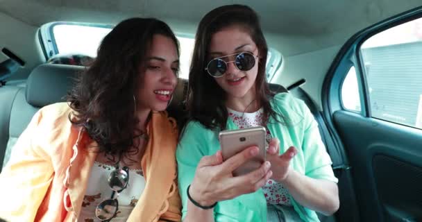 Female Friends Backseat Taxi Car Looking Browsing Internet Smartphone Device — 图库视频影像