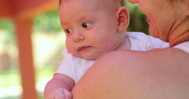 Mother holding newborn baby infant outdoors cute infant face