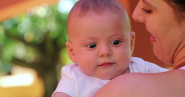 Mother holding newborn baby infant outdoors cute infant face