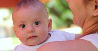 Infant newborn baby changing emotions outdoors held by mom