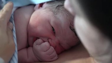 Doğumdan hemen sonra yeni doğan bebek yüzü. Doğumdan dakikalar sonra dünyaya geliyor. Annenin teniyle temasta bulunuyor.