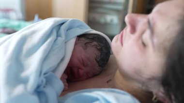 Doğumdan hemen sonra hastanedeki klinikte annesinin göğsünde ağlayan yeni doğmuş bir bebeğin dünyaya geldiği gerçek hayatta gerçek doğum sahnesi.