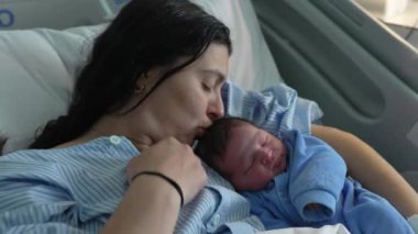 Anne, doğumdan hemen sonra yeni doğmuş bebeği öpüyor. Hastanede kucağında bebeğini kucağına alan ve ona bakan anne tarafından büyütülüyor.